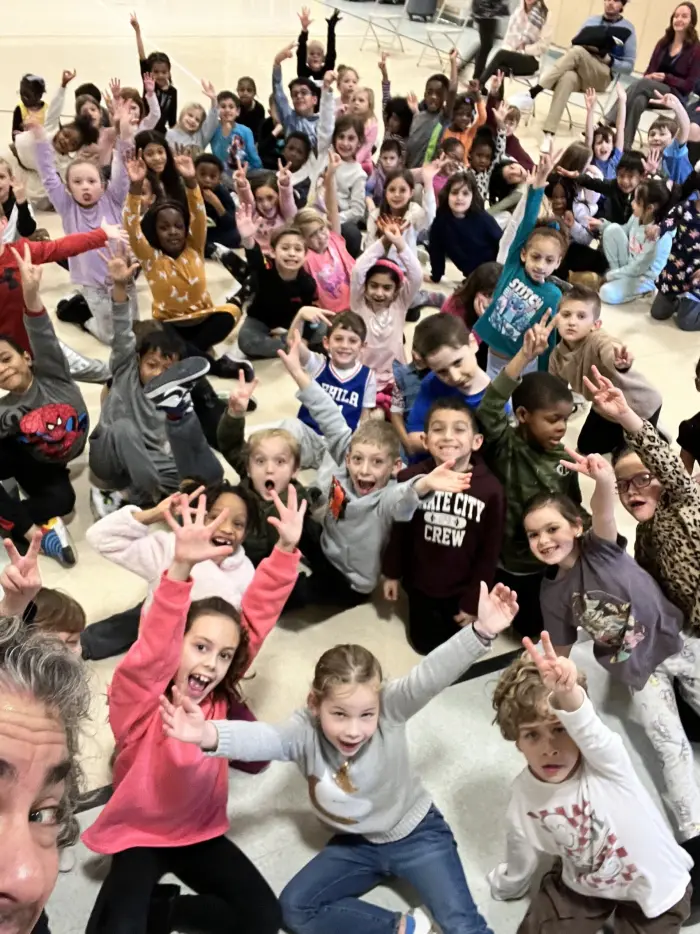 A gym full of students cheering at a school assembly